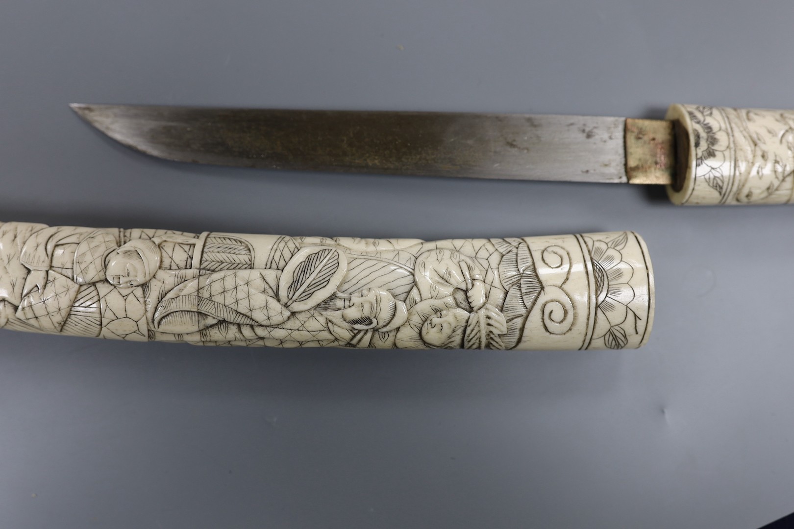 A Japanese carved bone tanto, c.1900, carved with numerous figures, overall 36cm